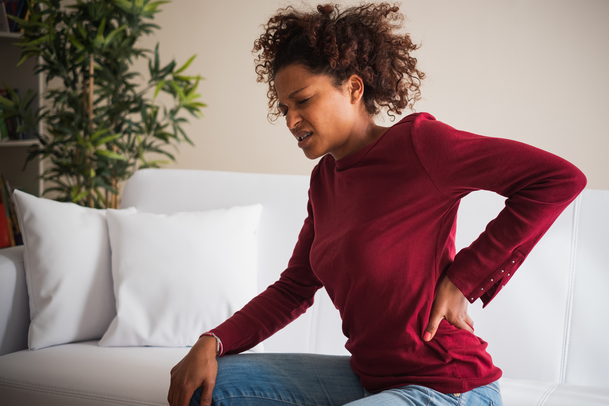 Back Neck pain. Painful woman holds with hand her lower back