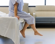 patient sitting on edge of hospital bed