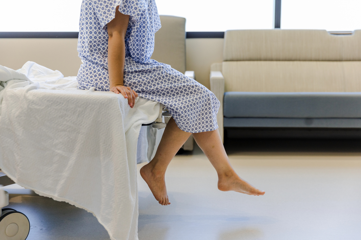 patient sitting on edge of hospital bed